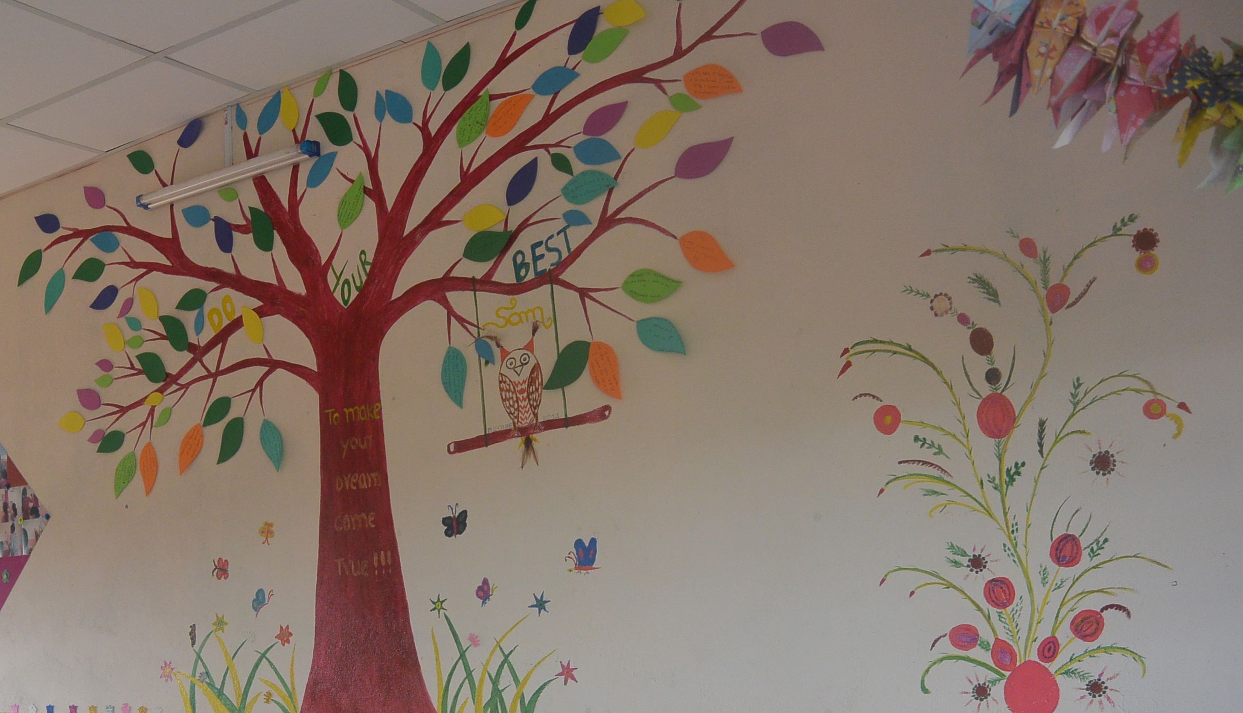 Buitenlandse vrijwilligers maken een muurtekening met de kinderen